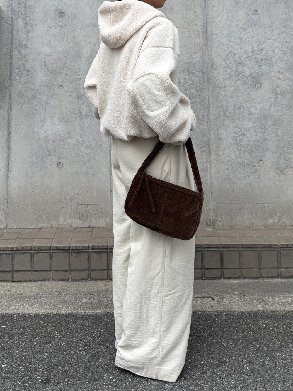 ホワイト系のパーカー、ホワイト系のその他パンツ、ブラウン系のハンドバッグを着用したレディースの秋コーディネートの4枚目の写真