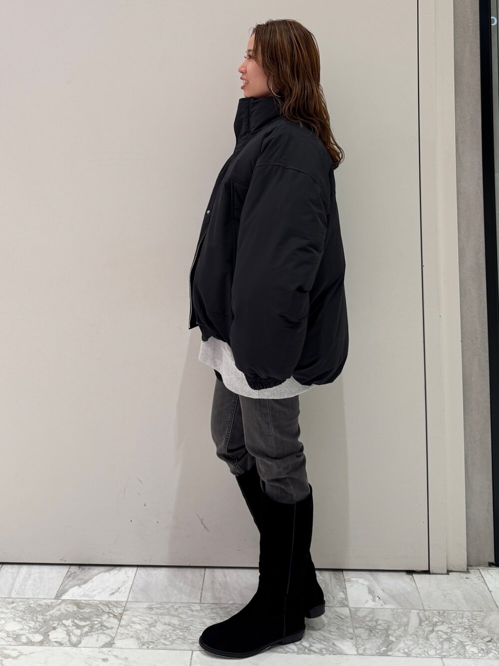 ブラック系のブルゾン、グレー系のスウェット、ブラック系のデニムパンツを着用したレディースの冬コーディネートの5枚目の写真