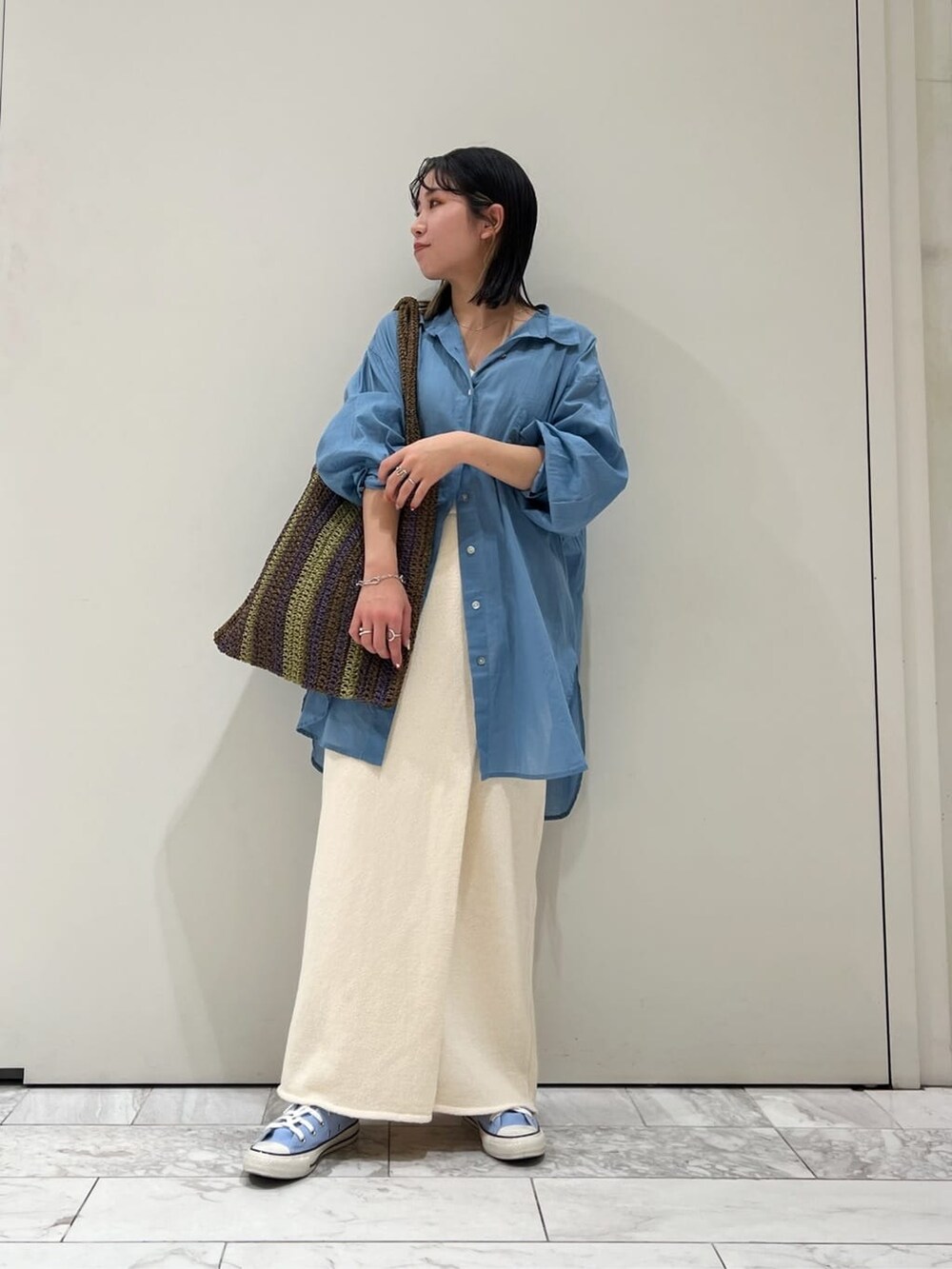 ブラウン系のトートバッグ、ホワイト系のスカート、ブルー系のシャツ/ブラウスを着用したレディースの春コーディネートの2枚目の写真
