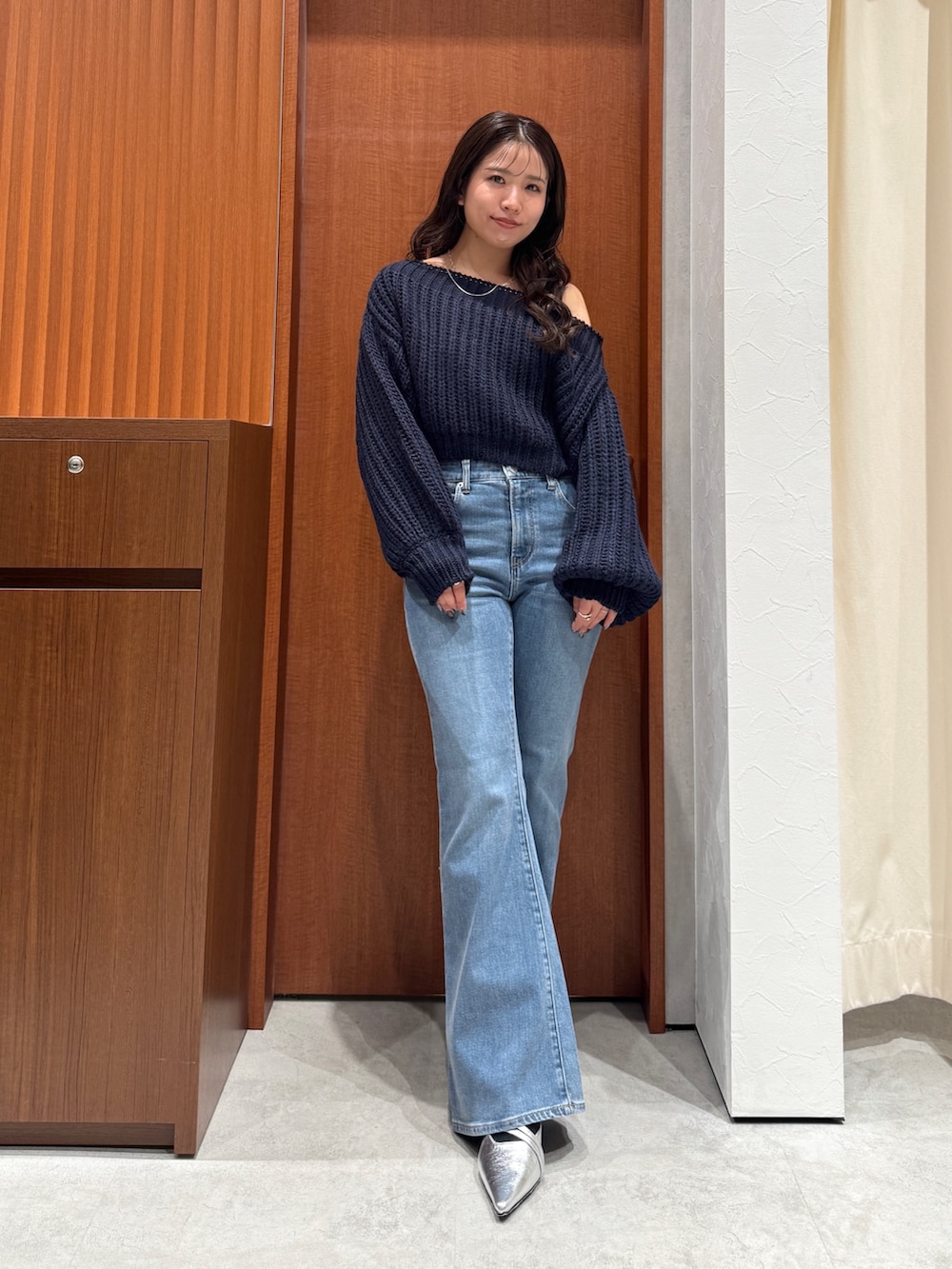 ブルー系のニット/セーター、ブルー系のデニムパンツ、シルバー系のパンプスを着用したレディースの秋コーディネートの6枚目の写真