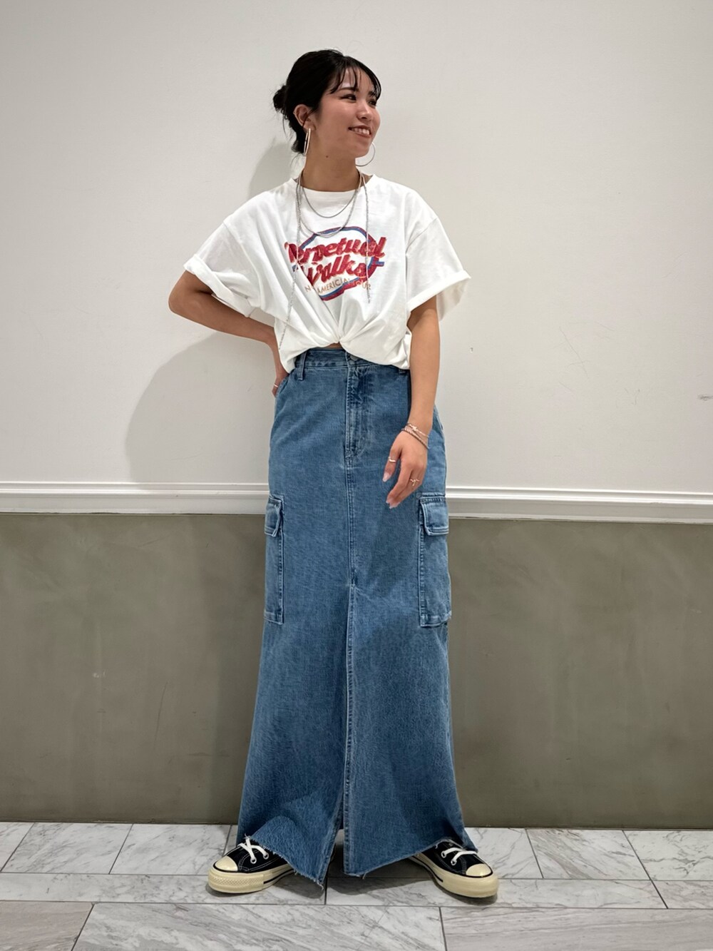 ブルー系のデニムスカート、ホワイト系のTシャツ/カットソー、ブルー系のスニーカーを着用したレディースの春コーディネートの5枚目の写真