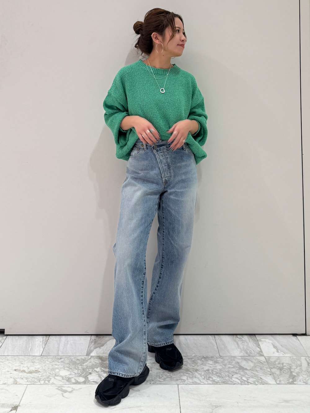 ブルー系のデニムパンツ、グリーン系のニット/セーター、シルバー系のネックレスを着用したレディースの冬コーディネートの5枚目の写真