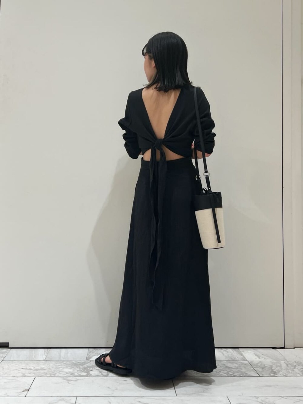 ブラック系のワンピース、ブラック系のショルダーバッグ、ブラック系のサンダルを着用したレディースの春コーディネートの3枚目の写真