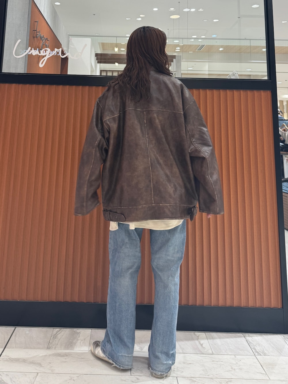 ブラウン系のブルゾン、ホワイト系のシャツ/ブラウス、ブルー系のデニムパンツを着用したレディースの秋コーディネートの3枚目の写真