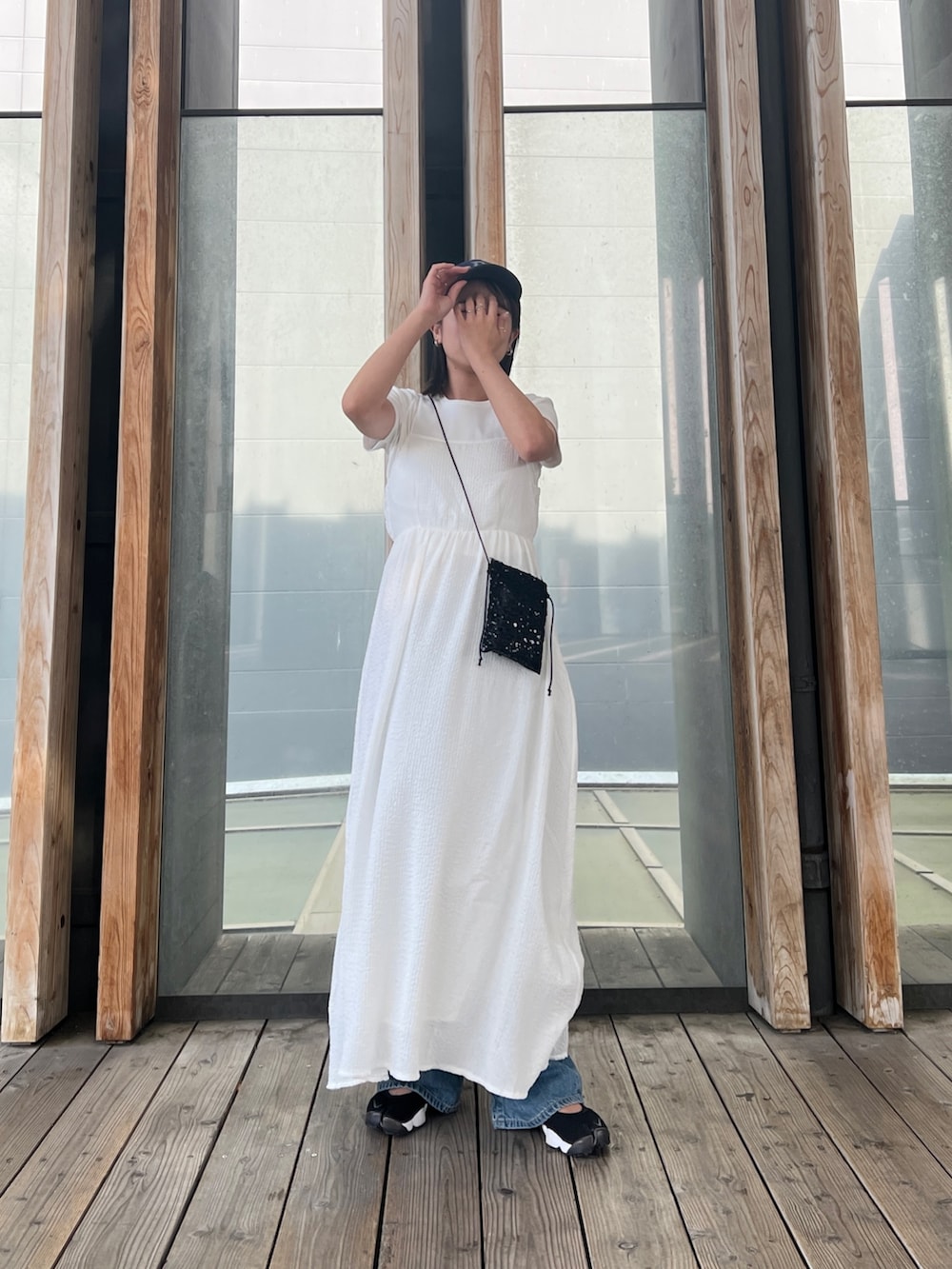 ホワイト系のTシャツ/カットソー、ホワイト系のワンピース、ブルー系のデニムパンツを着用したレディースの春コーディネートの4枚目の写真