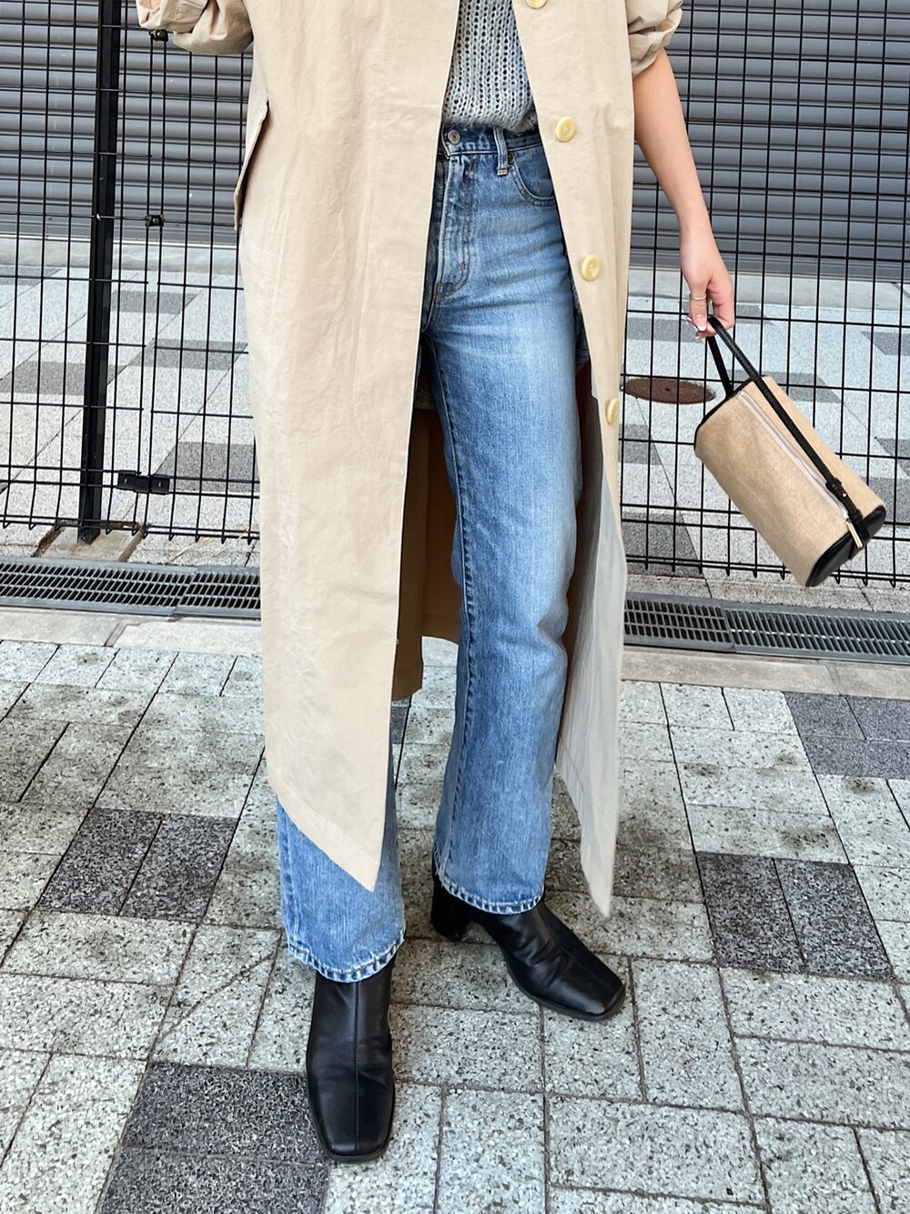 ブルー系のデニムパンツ、ベージュ系のステンカラーコート、グレー系のニット/セーターを着用したレディースの冬コーディネートの6枚目の写真