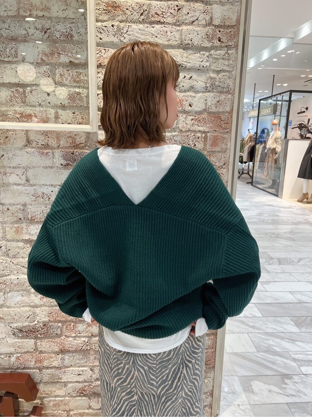 ホワイト系のTシャツ/カットソー、ブルー系のスカート、グリーン系のニット/セーターを着用したレディースの秋コーディネートの9枚目の写真