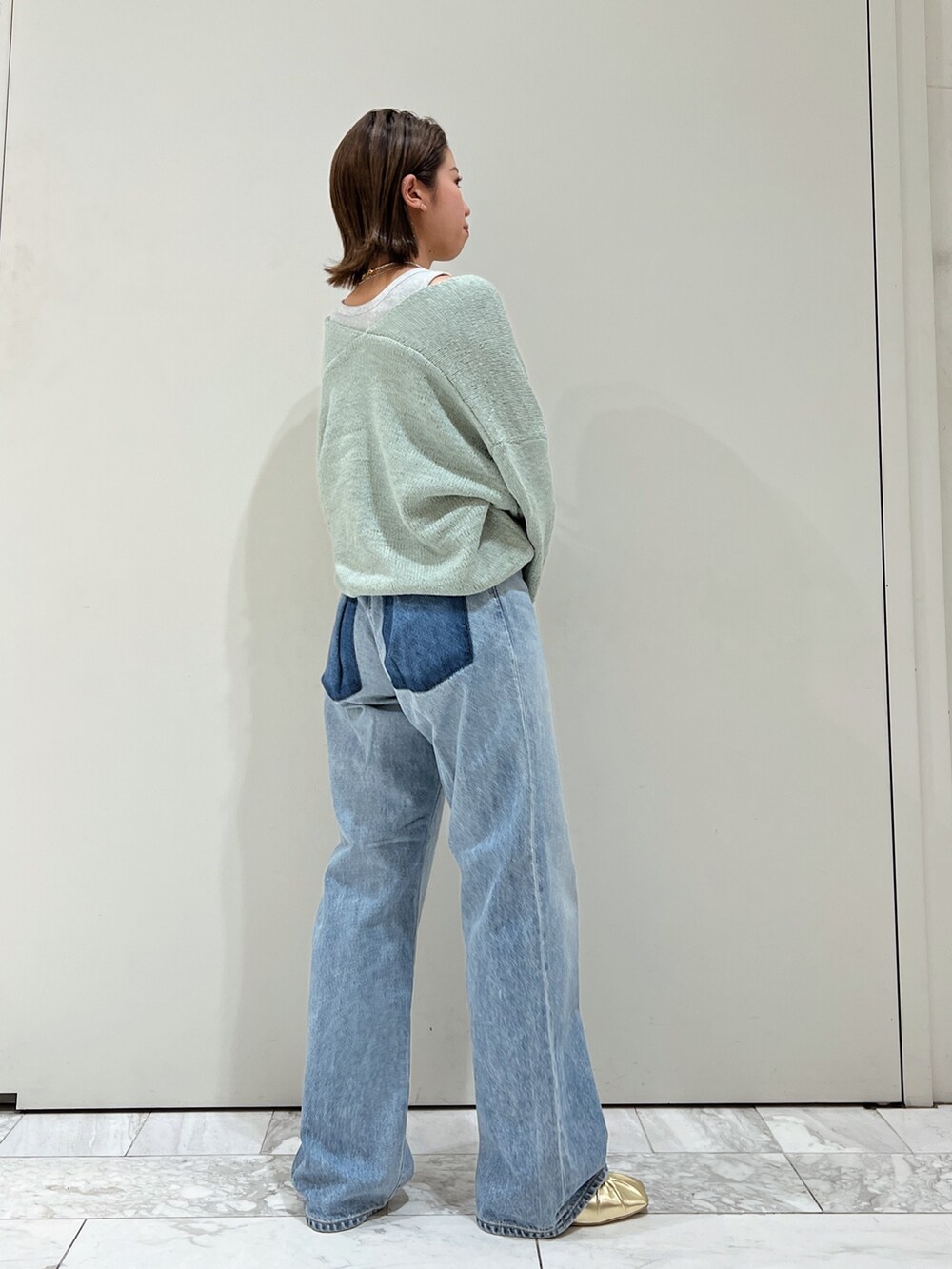 ブルー系のデニムパンツ、イエロー系のパンプス、グリーン系のニット/セーターを着用したレディースの冬コーディネートの3枚目の写真