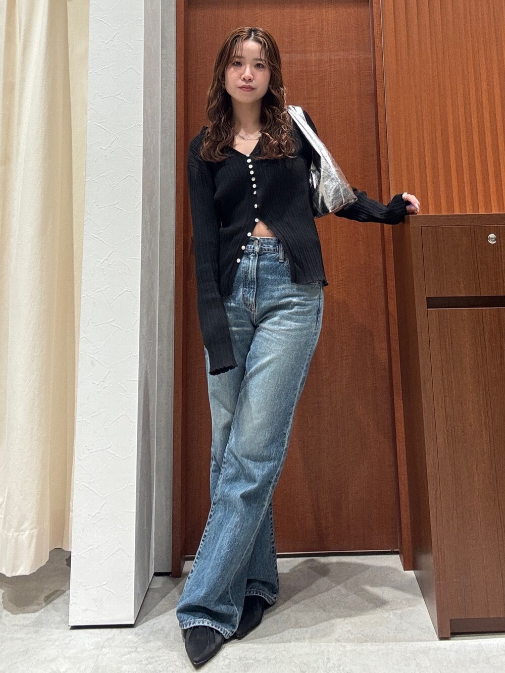 ブルー系のデニムパンツ、ブラック系のカーディガン/ボレロ、ブラック系のパンプスを着用したレディースの春コーディネートの6枚目の写真