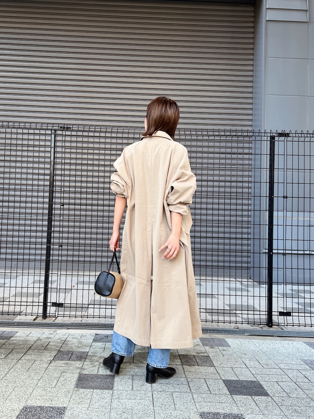 ブルー系のデニムパンツ、ベージュ系のステンカラーコート、グレー系のニット/セーターを着用したレディースの冬コーディネートの5枚目の写真