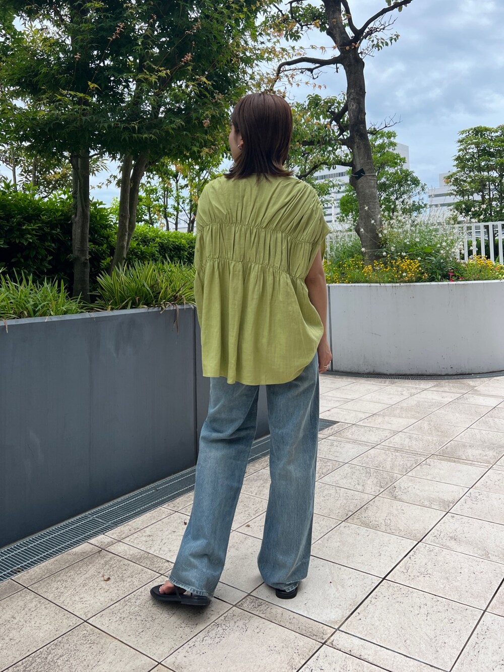 グリーン系のシャツ/ブラウス、ブラック系のキャミソール、ブルー系のデニムパンツを着用したレディースの夏コーディネートの4枚目の写真