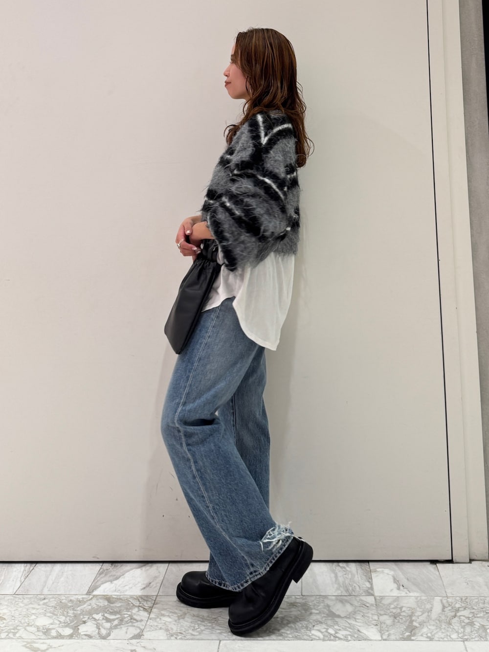 ブラック系のニット/セーター、ホワイト系のTシャツ/カットソー、ブルー系のデニムパンツを着用したレディースの冬コーディネートの5枚目の写真