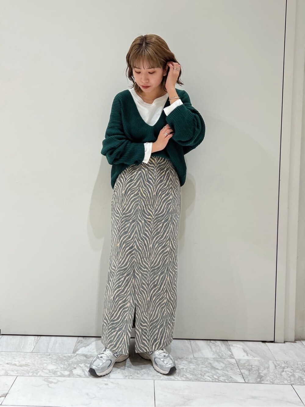 ホワイト系のTシャツ/カットソー、ブルー系のスカート、グリーン系のニット/セーターを着用したレディースの秋コーディネートの3枚目の写真