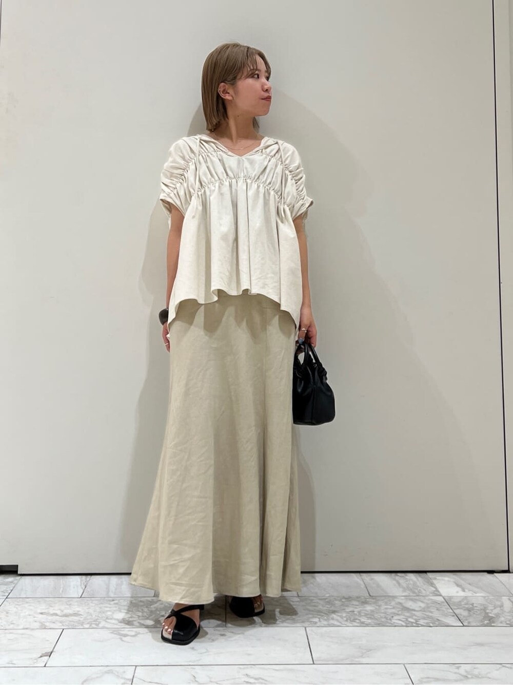 ブラック系のサンダル、ベージュ系のスカート、ホワイト系のシャツ/ブラウスを着用したレディースの夏コーディネートの2枚目の写真