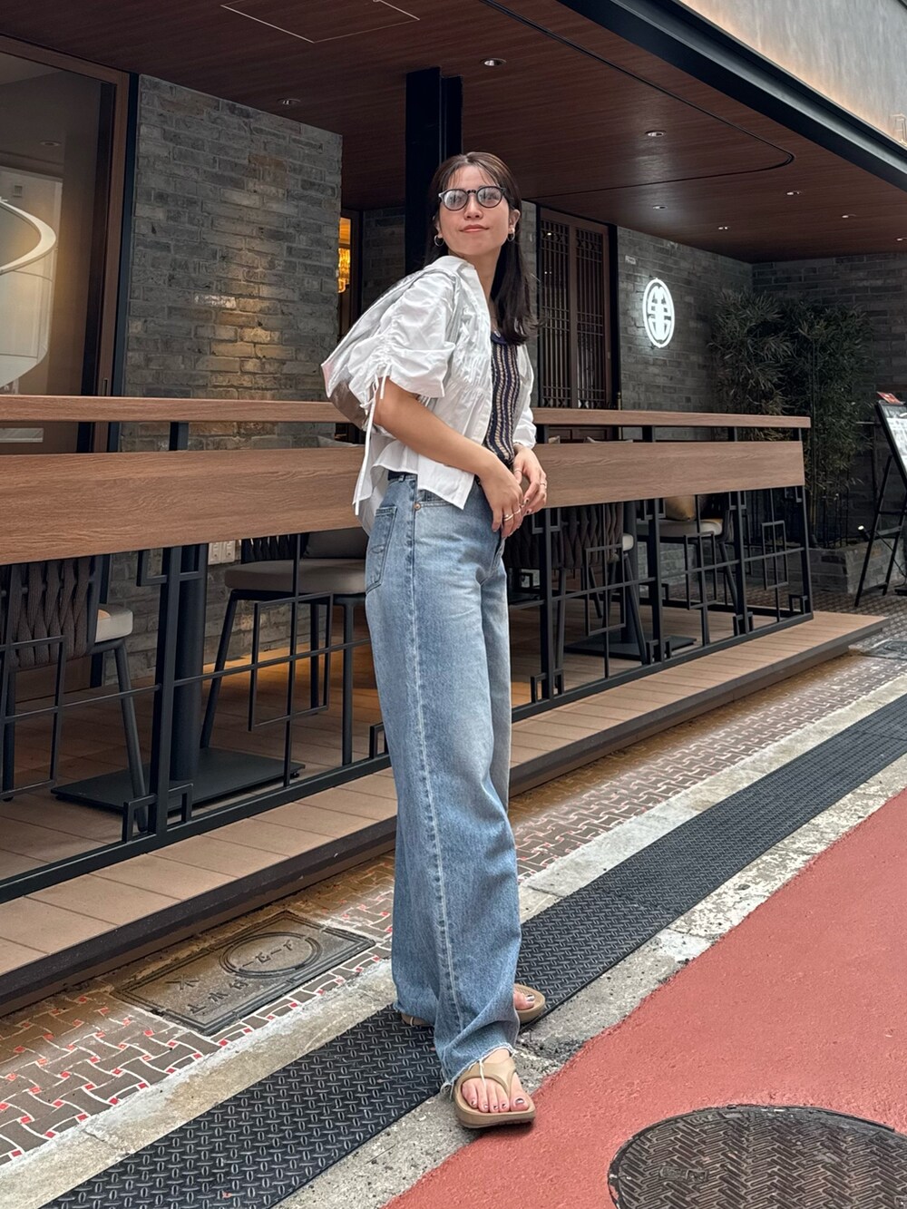 ブルー系のデニムパンツ、ホワイト系のシャツ/ブラウス、シルバー系のハンドバッグを着用したレディースの春コーディネートの6枚目の写真