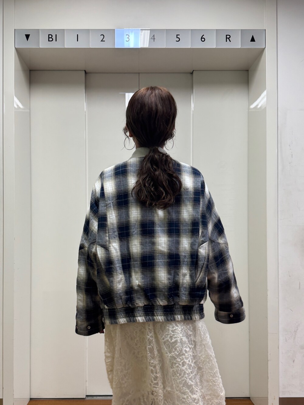 ベージュ系のブルゾン、ホワイト系のワンピース、ブルー系のデニムパンツを着用したレディースの冬コーディネートの5枚目の写真