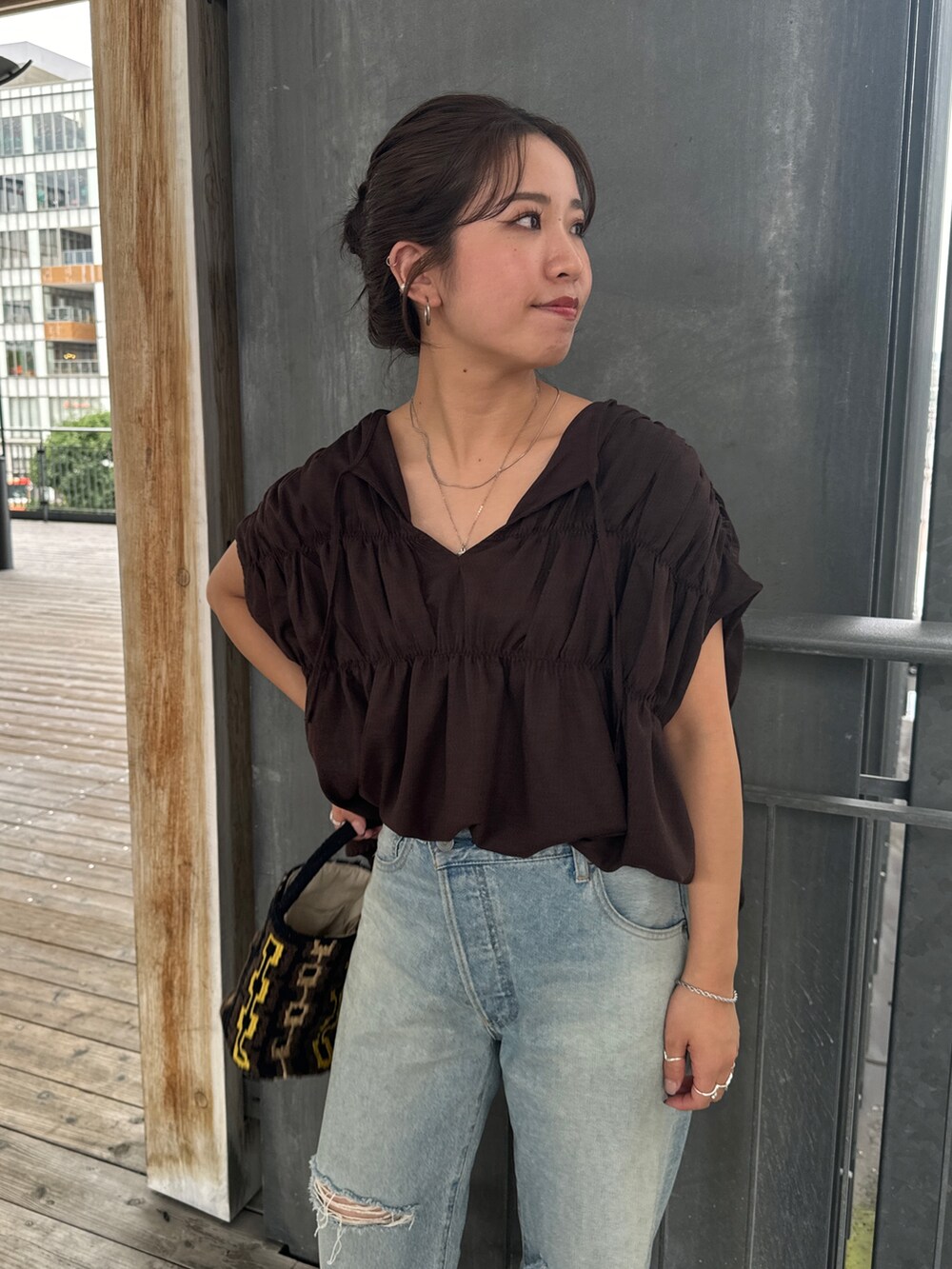 ブルー系のデニムパンツ、ホワイト系のサンダル、ブラウン系のハンドバッグを着用したレディースの夏コーディネートの5枚目の写真