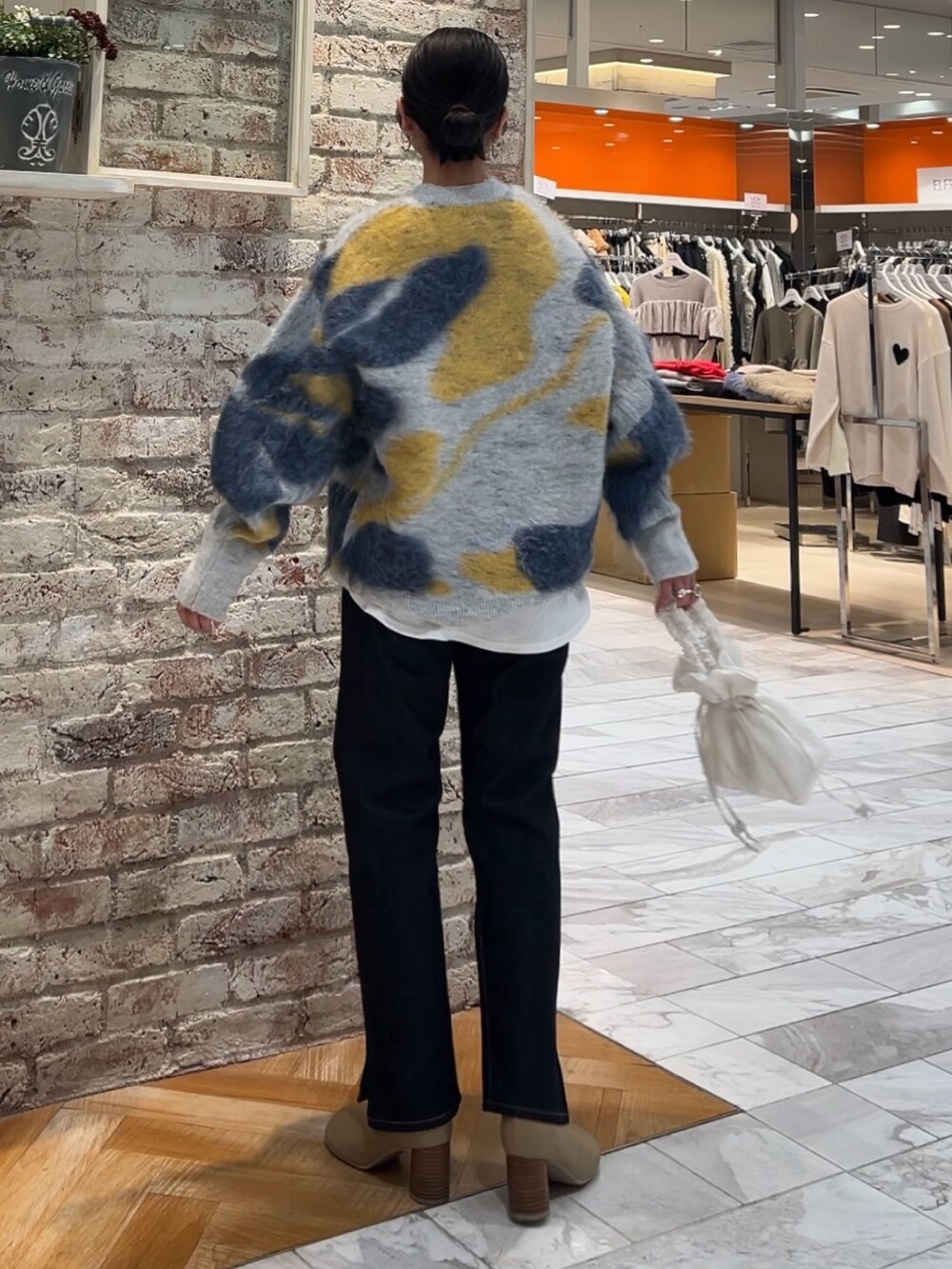 ブルー系のニット/セーター、ホワイト系のハンドバッグ、ブルー系のデニムパンツを着用したレディースの秋コーディネートの3枚目の写真