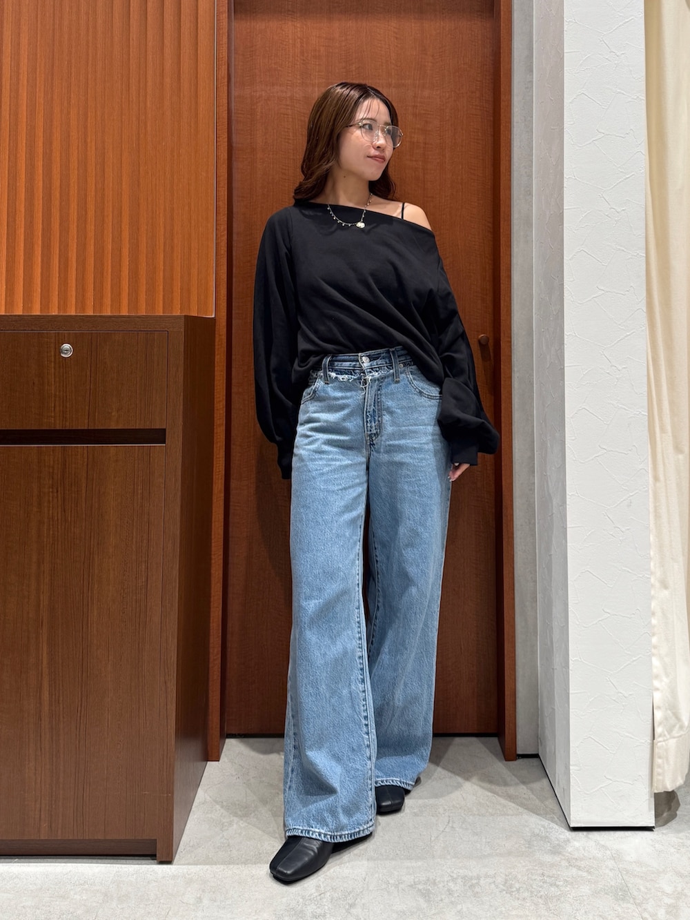 ブルー系のデニムパンツ、ブラック系のスウェット、シルバー系のメガネを着用したレディースの秋コーディネートの5枚目の写真