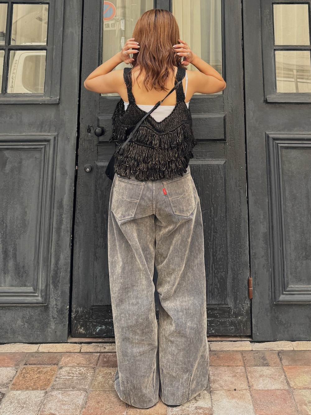 ベージュ系のデニムパンツ、ブラック系のニット/セーター、ベージュ系のスリッポンを着用したレディースの秋コーディネートの5枚目の写真