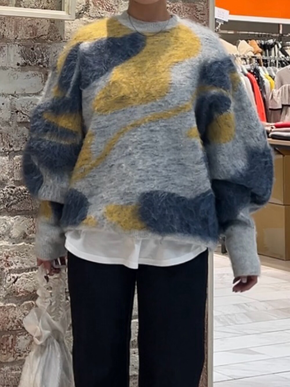 ブルー系のニット/セーター、ホワイト系のハンドバッグ、ブルー系のデニムパンツを着用したレディースの秋コーディネートの2枚目の写真