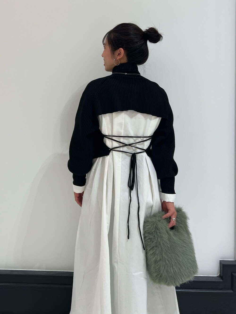 ブラック系のワンピース、グリーン系のハンドバッグ、ブラウン系のブーツを着用したレディースの冬コーディネートの6枚目の写真