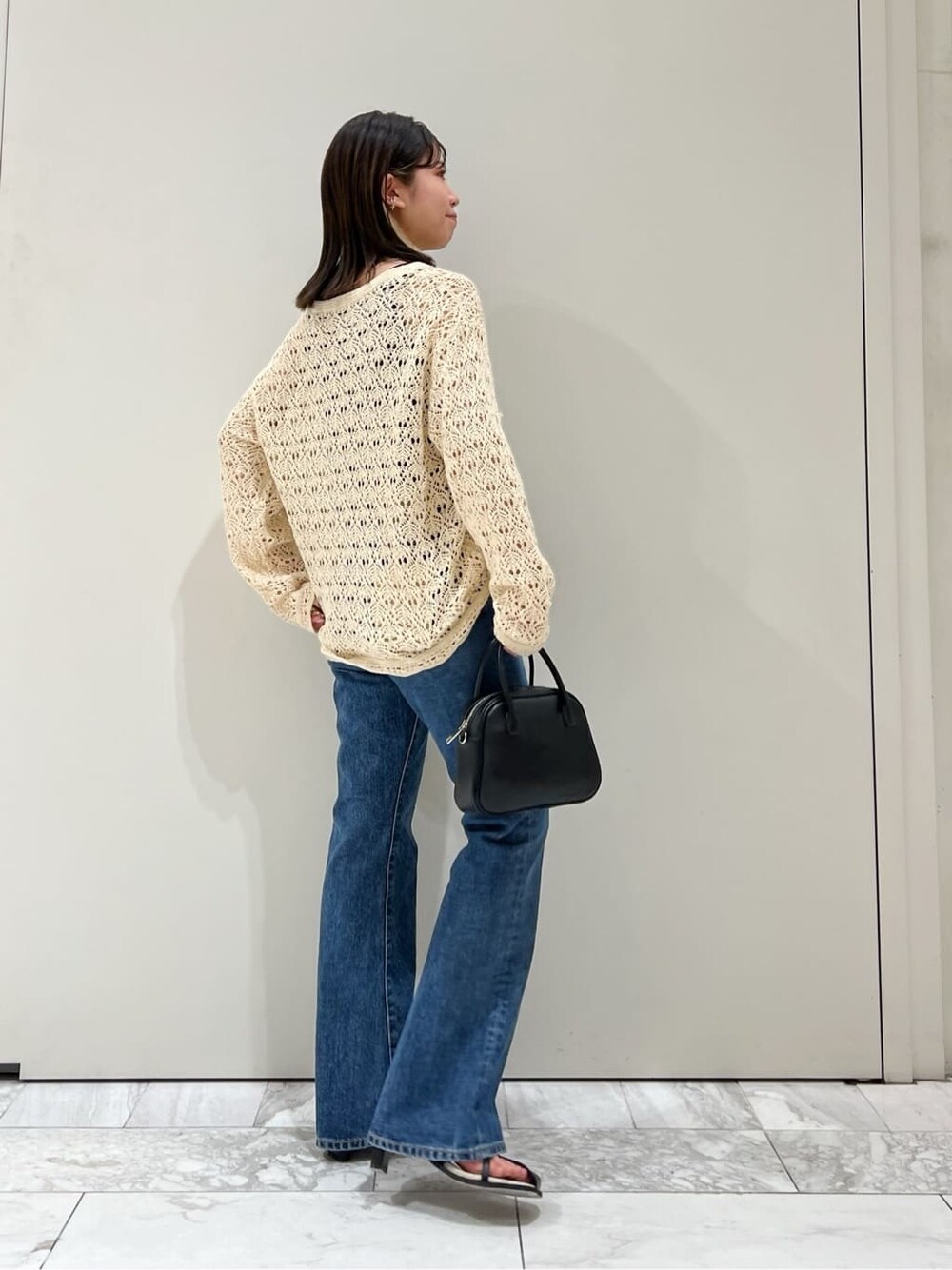 ブラック系のサンダル、ブラック系のハンドバッグ、ブルー系のデニムパンツを着用したレディースの春コーディネートの3枚目の写真