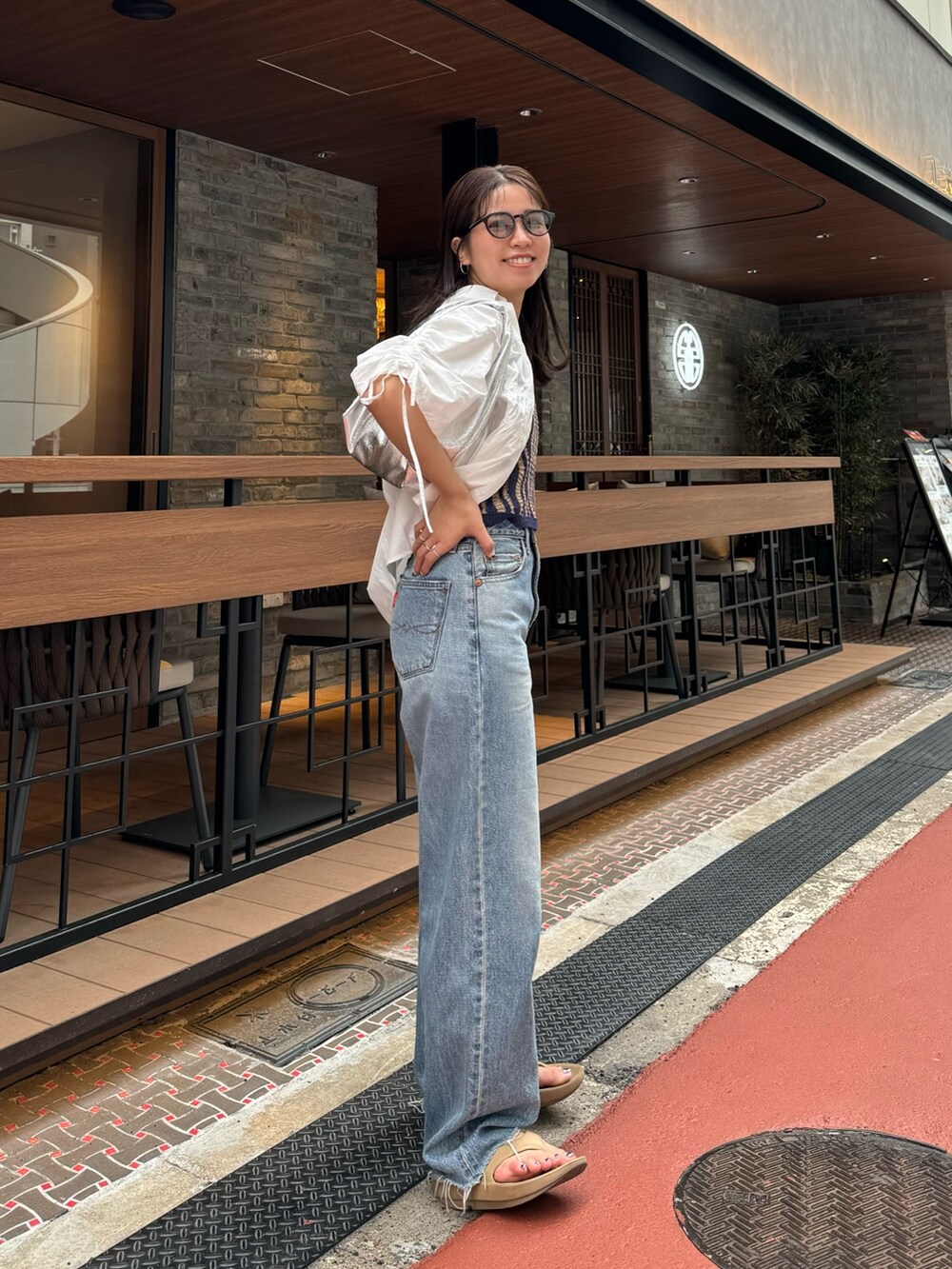 ブルー系のデニムパンツ、ホワイト系のシャツ/ブラウス、シルバー系のハンドバッグを着用したレディースの春コーディネートの7枚目の写真