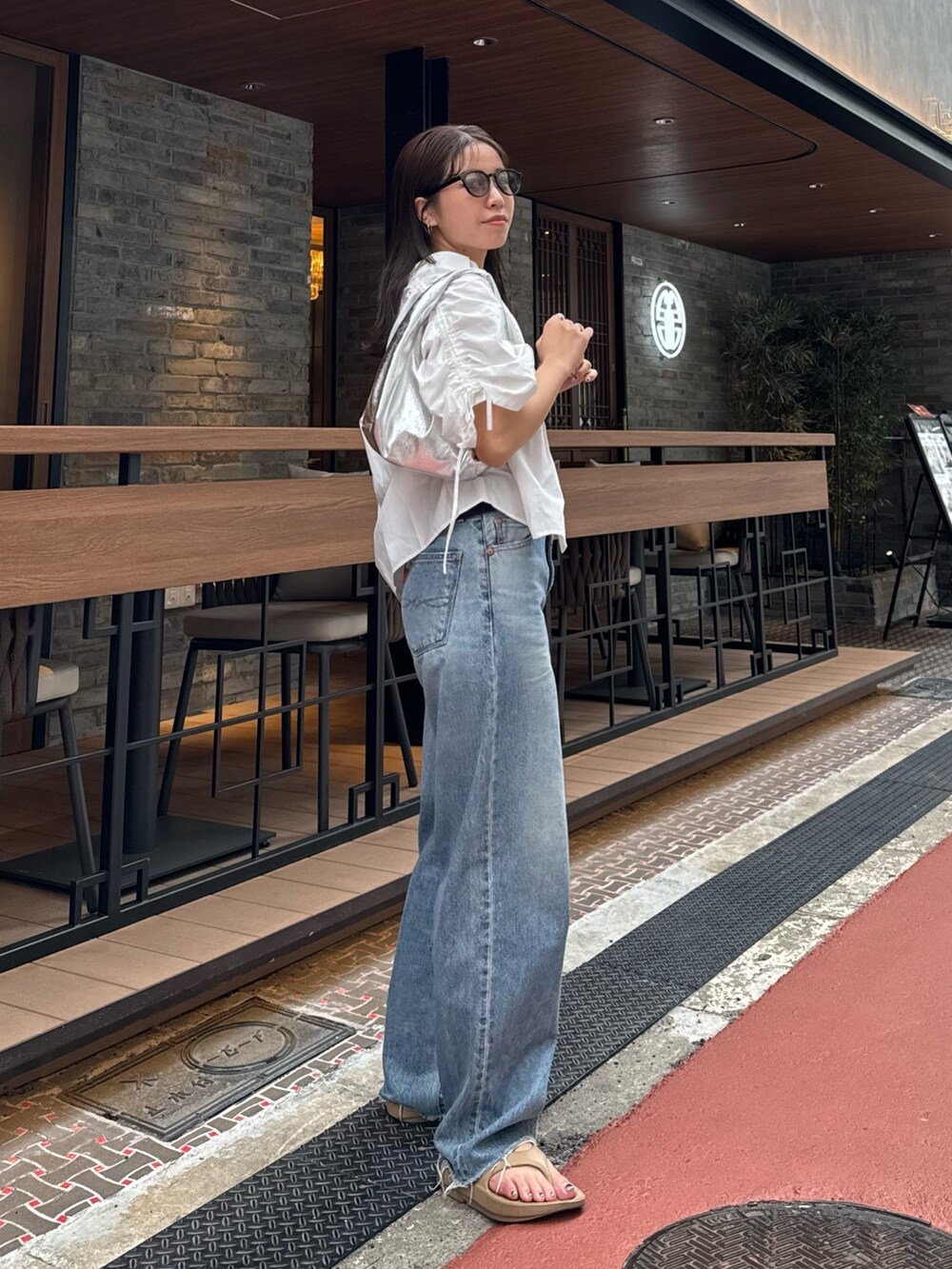 ブルー系のデニムパンツ、ホワイト系のシャツ/ブラウス、シルバー系のハンドバッグを着用したレディースの春コーディネートの3枚目の写真