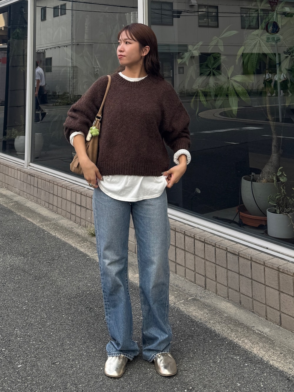 ホワイト系のTシャツ/カットソー、ブラウン系のニット/セーター、ブルー系のデニムパンツを着用したレディースの秋コーディネートの2枚目の写真