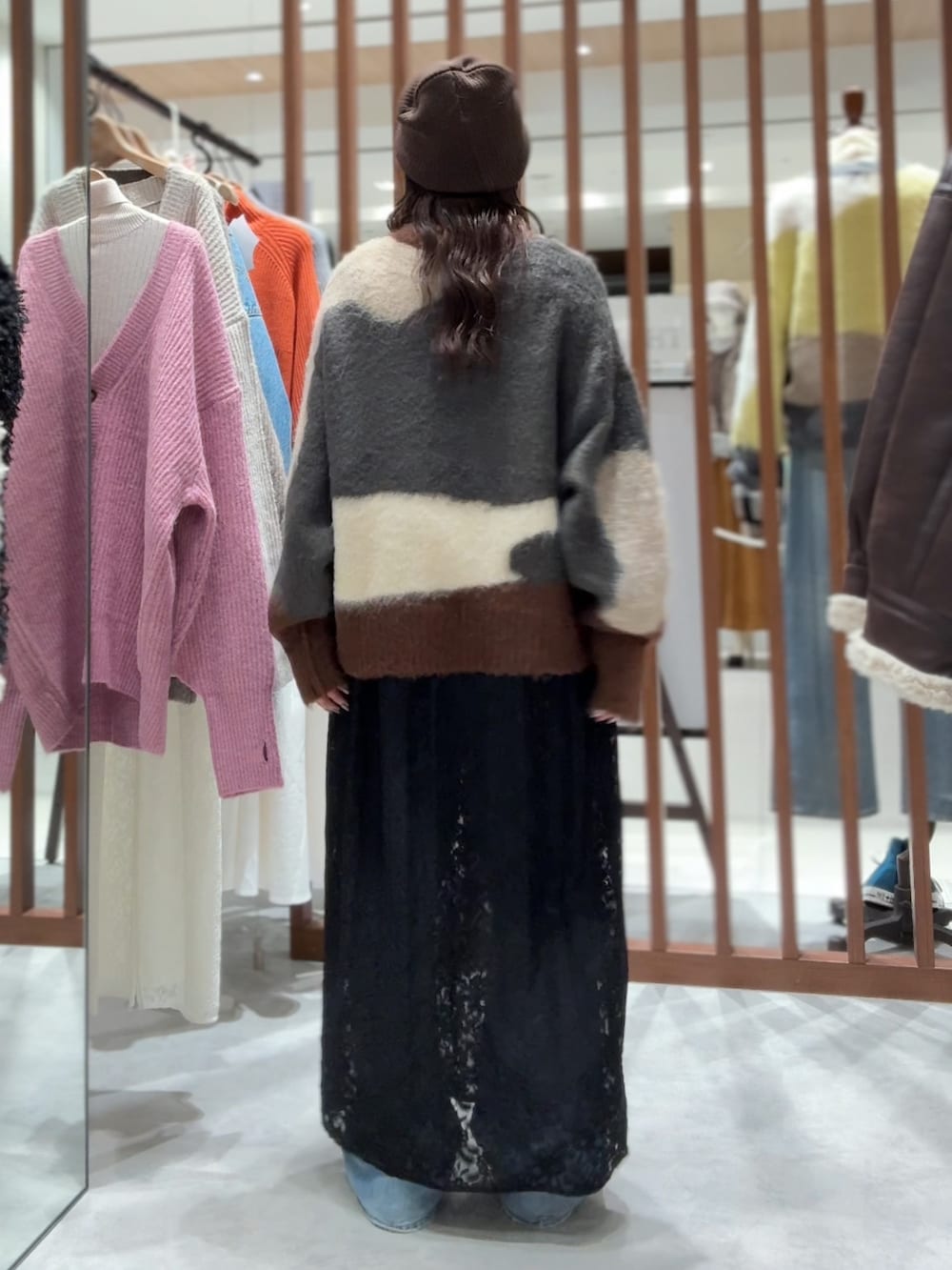 グレー系のニット/セーター、ブラック系のワンピース、ブルー系のデニムパンツを着用したレディースの秋コーディネートの8枚目の写真