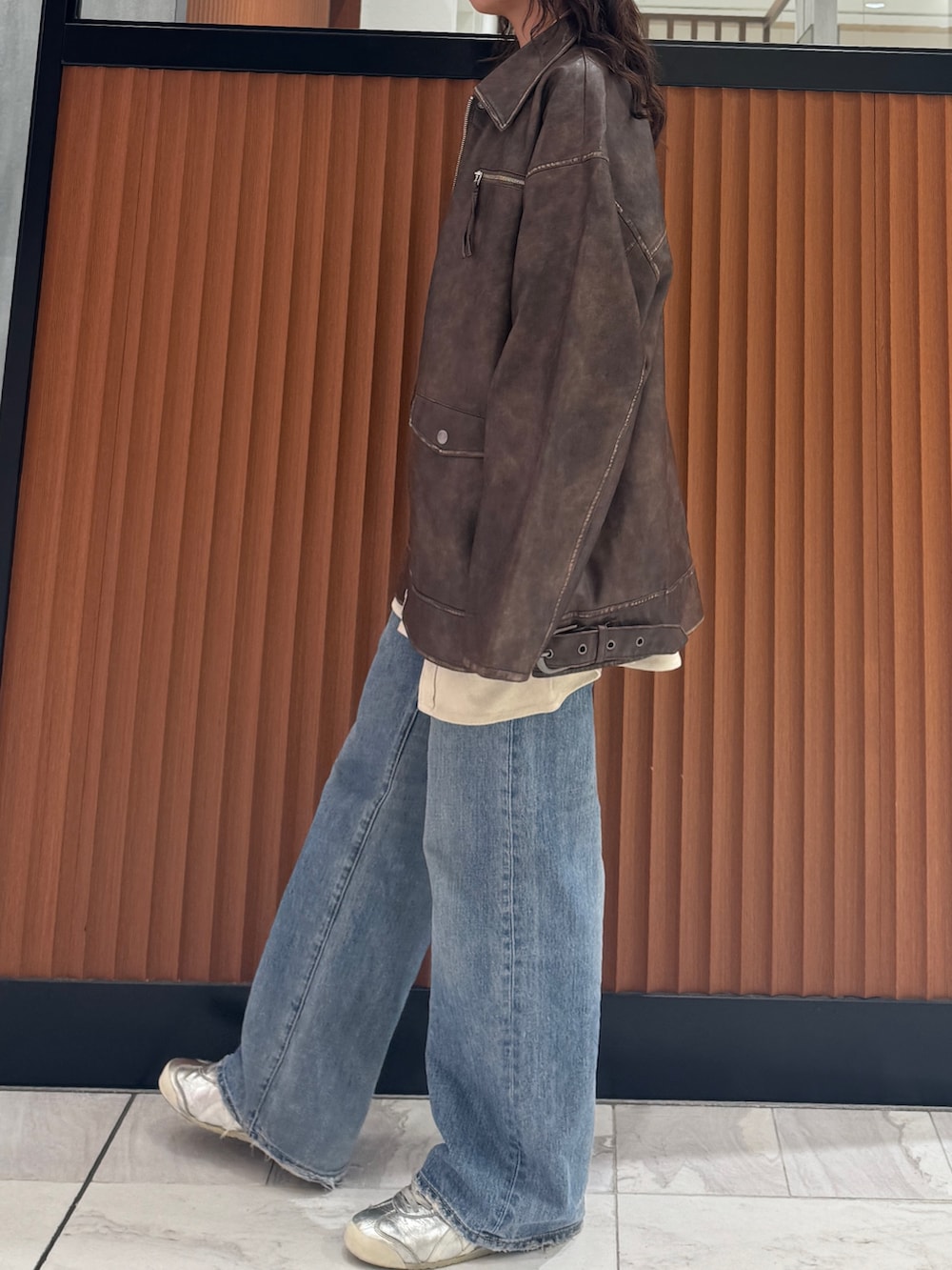 ブラウン系のブルゾン、ホワイト系のシャツ/ブラウス、ブルー系のデニムパンツを着用したレディースの秋コーディネートの4枚目の写真