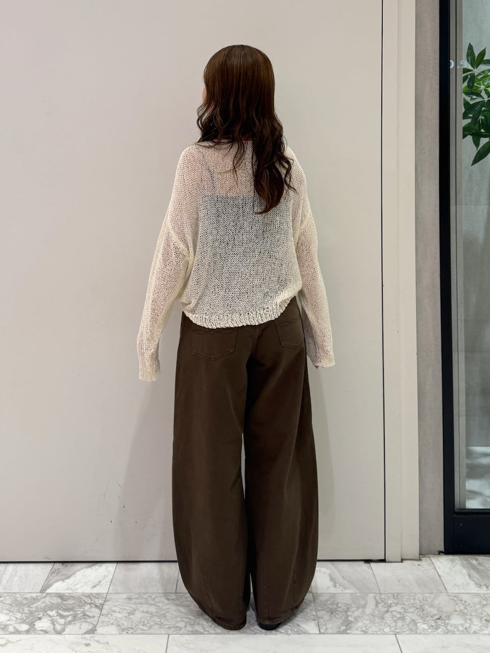 ブラウン系のデニムパンツ、ホワイト系のニット/セーター、ブラック系のサンダルを着用したレディースの秋コーディネートの6枚目の写真