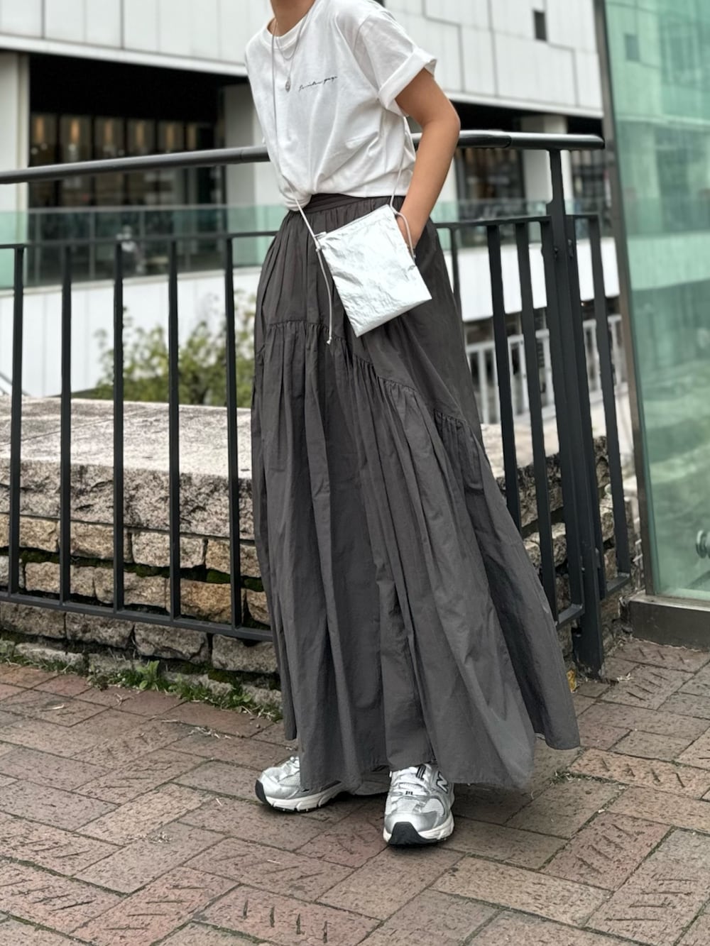 シルバー系のショルダーバッグ、ホワイト系のTシャツ/カットソー、グレー系のスカートを着用したレディースの春コーディネートの3枚目の写真