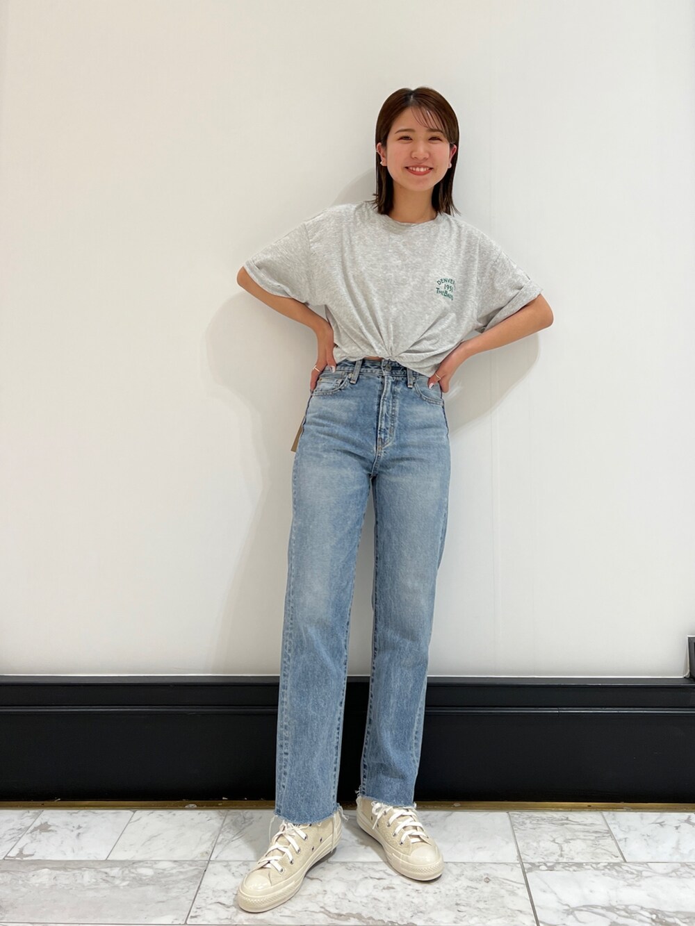 ブルー系のデニムパンツ、グレー系のTシャツ/カットソー、ホワイト系のスニーカーを着用したレディースの春コーディネートの3枚目の写真