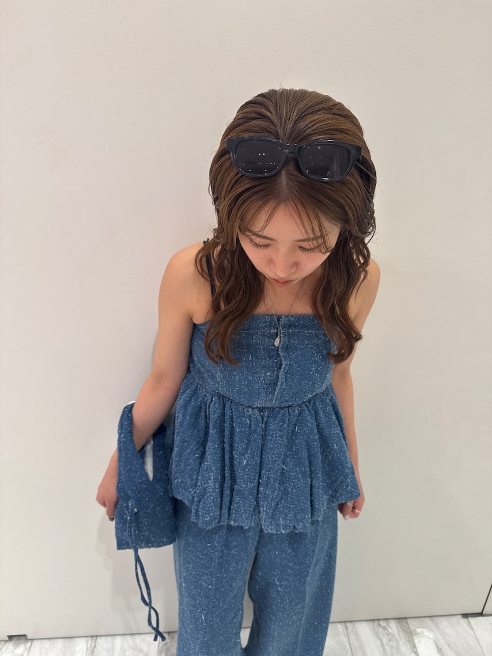 ブルー系のチューブトップ、ブルー系のデニムパンツ、ブルー系のハンドバッグを着用したレディースの春コーディネートの9枚目の写真