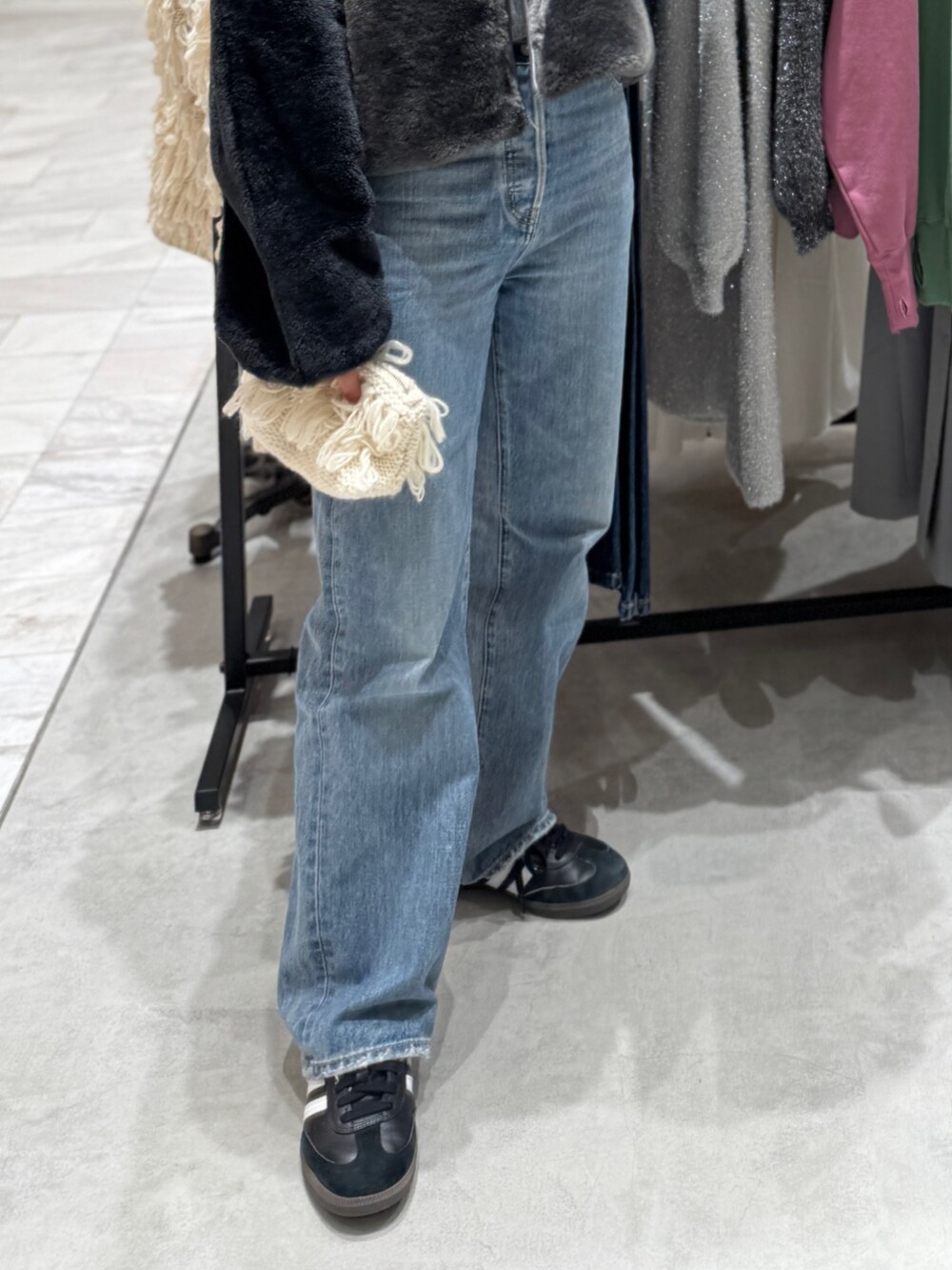 グレー系のブルゾン、グレー系のニット/セーター、ブルー系のデニムパンツを着用したレディースの秋コーディネートの6枚目の写真