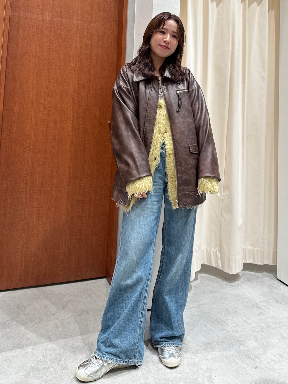 ブルー系のデニムパンツ、イエロー系のカーディガン/ボレロ、ブラウン系のブルゾンを着用したレディースの秋コーディネートの2枚目の写真