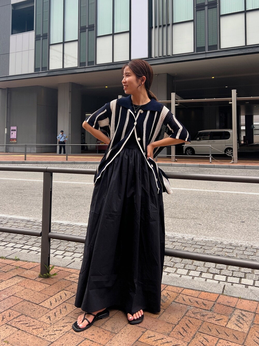 ブラック系のワンピース、ブルー系のカーディガン/ボレロ、ブラック系のサンダルを着用したレディースの春コーディネートの4枚目の写真