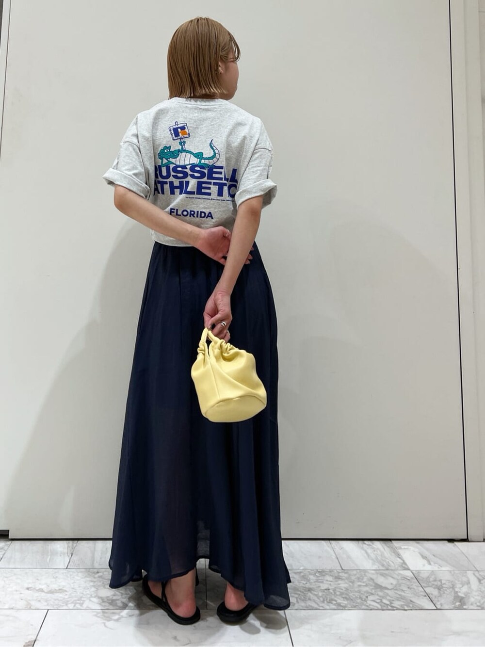 ブラック系のサンダル、ブルー系のスカート、イエロー系のハンドバッグを着用したレディースの春コーディネートの6枚目の写真