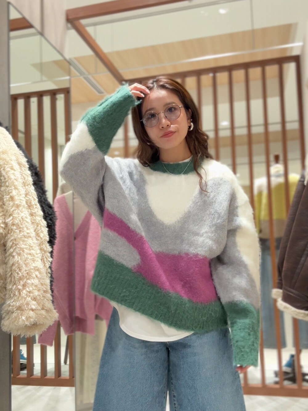 グリーン系のニット/セーター、ホワイト系のTシャツ/カットソー、ブルー系のデニムパンツを着用したレディースの秋コーディネートの2枚目の写真