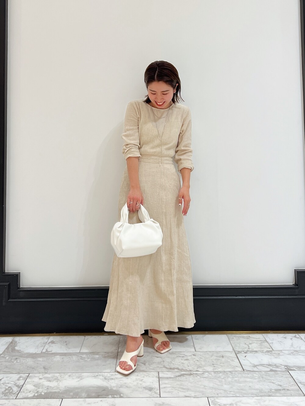ホワイト系のベスト、ホワイト系のワンピース、ホワイト系のハンドバッグを着用したレディースの春コーディネートの6枚目の写真