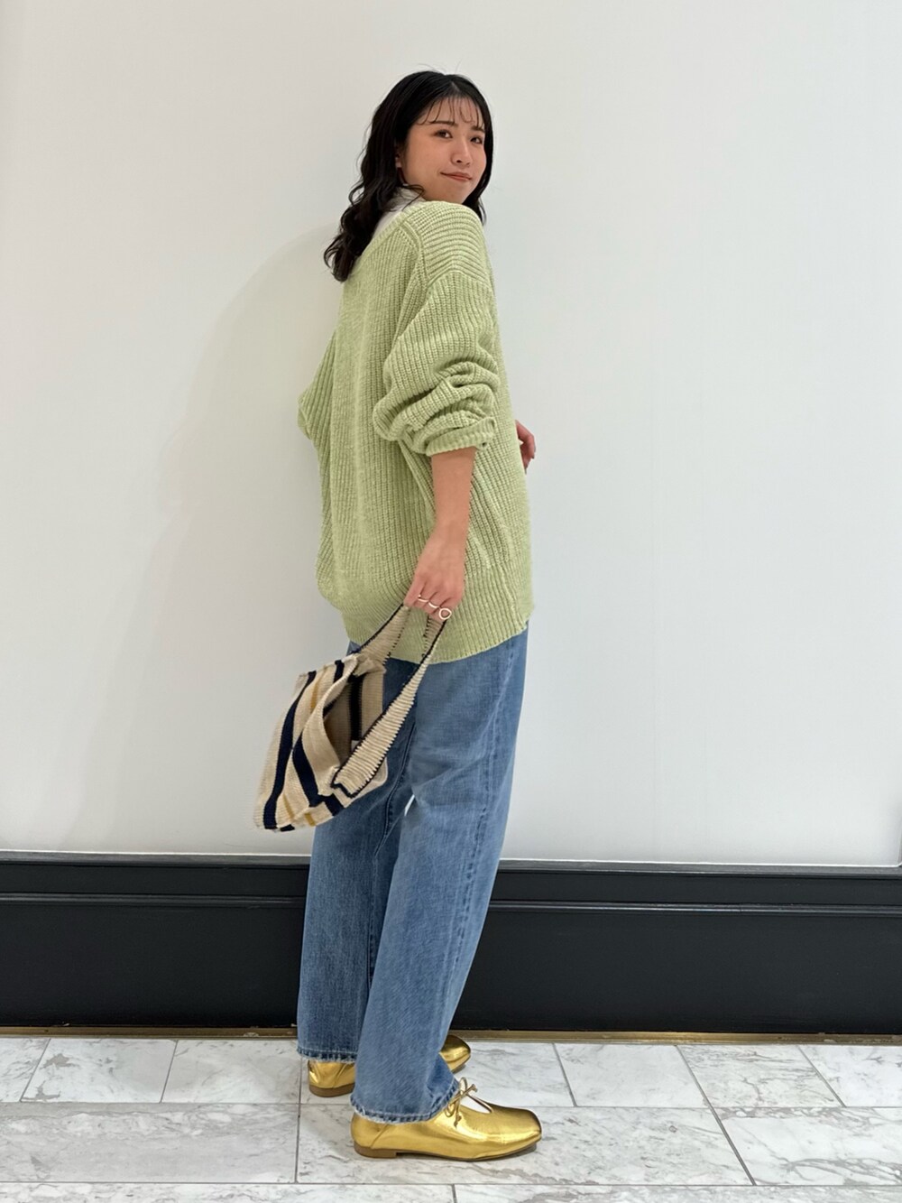 グリーン系のカーディガン/ボレロ、ホワイト系のハンドバッグ、ブルー系のデニムパンツを着用したレディースの冬コーディネートの5枚目の写真