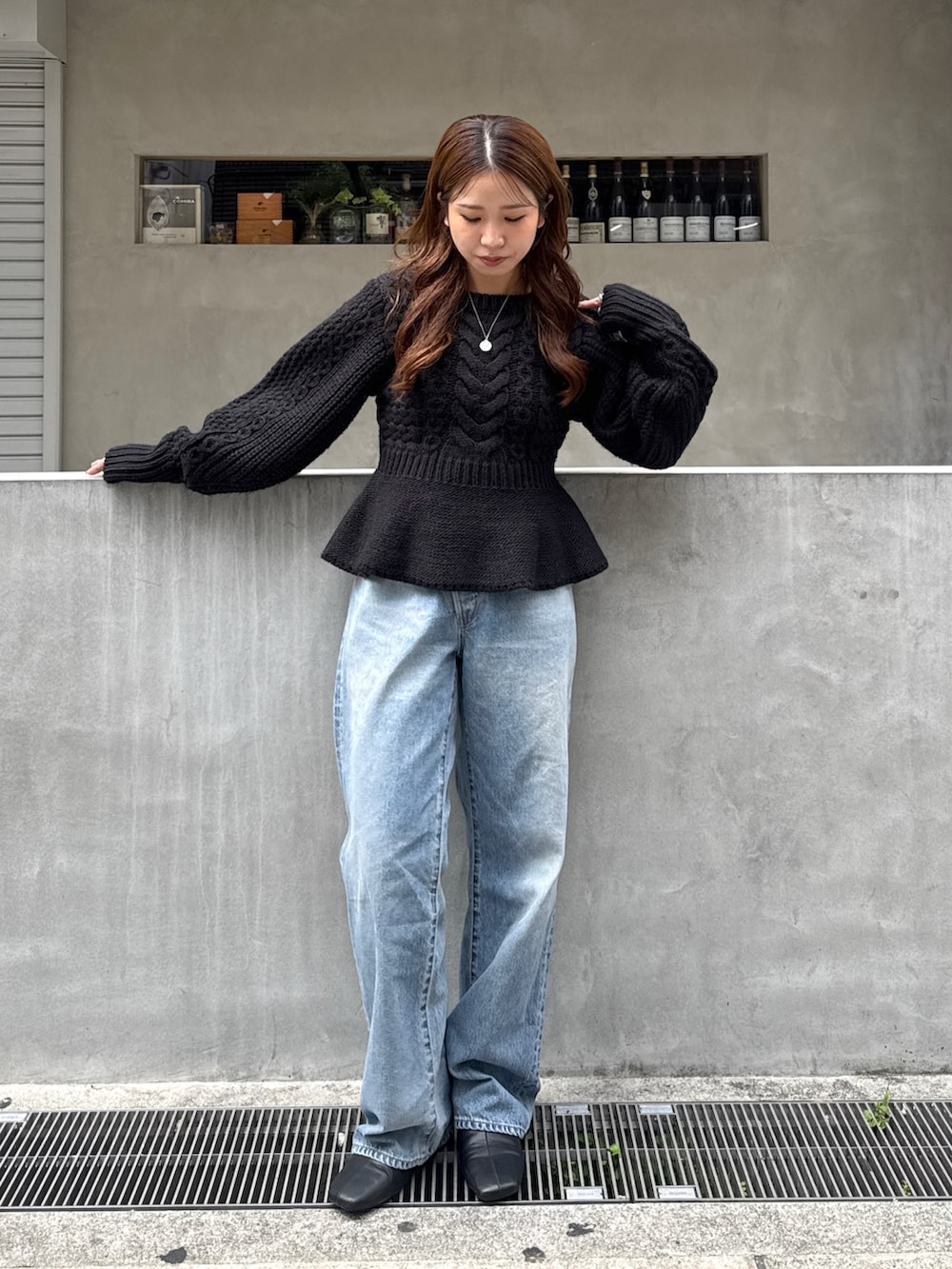 ブラック系のニット/セーター、ブルー系のデニムパンツ、ブラック系のサンダルを着用したレディースの秋コーディネートの5枚目の写真
