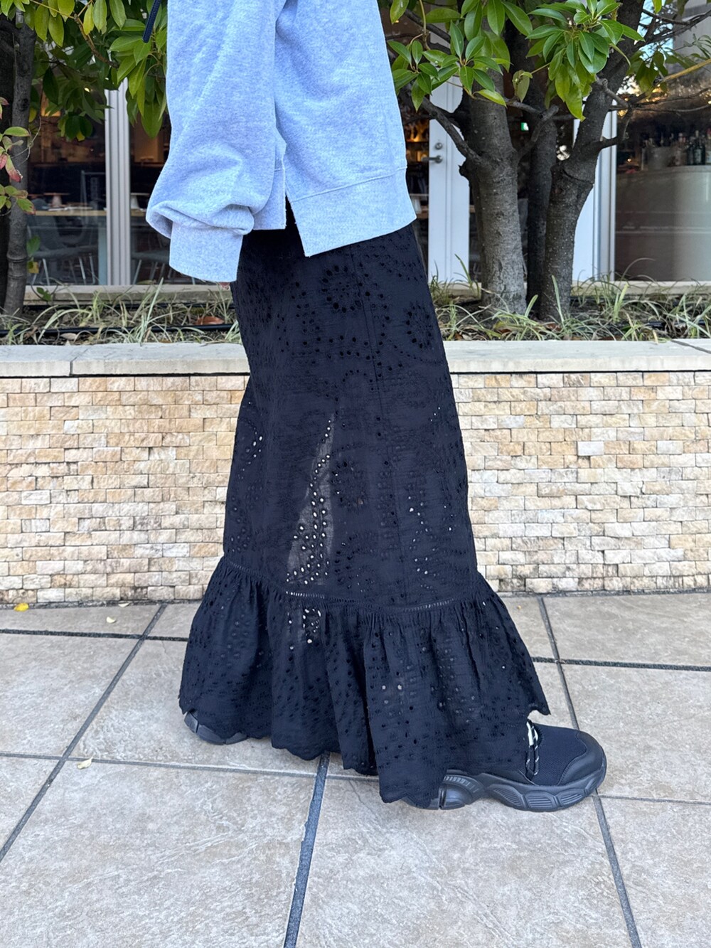 ブラック系のスカート、グレー系のスウェット、ブラック系のスニーカーを着用したレディースの冬コーディネートの9枚目の写真