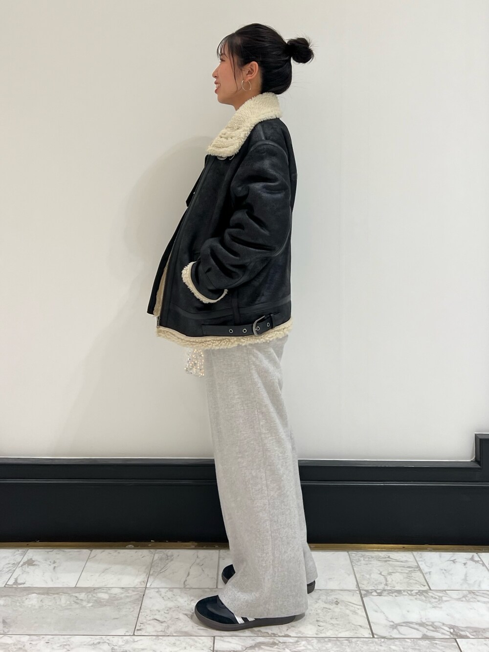 ホワイト系のハンドバッグ、グレー系のニット/セーター、ブラック系のムートンコートを着用したレディースの冬コーディネートの9枚目の写真