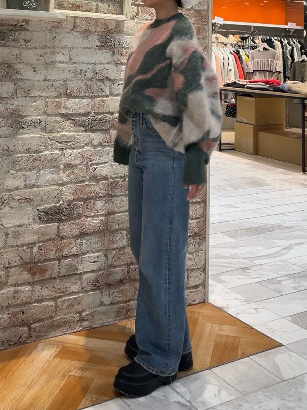 ブラック系のブーツ、グリーン系のニット/セーター、ブルー系のデニムパンツを着用したレディースの秋コーディネートの4枚目の写真