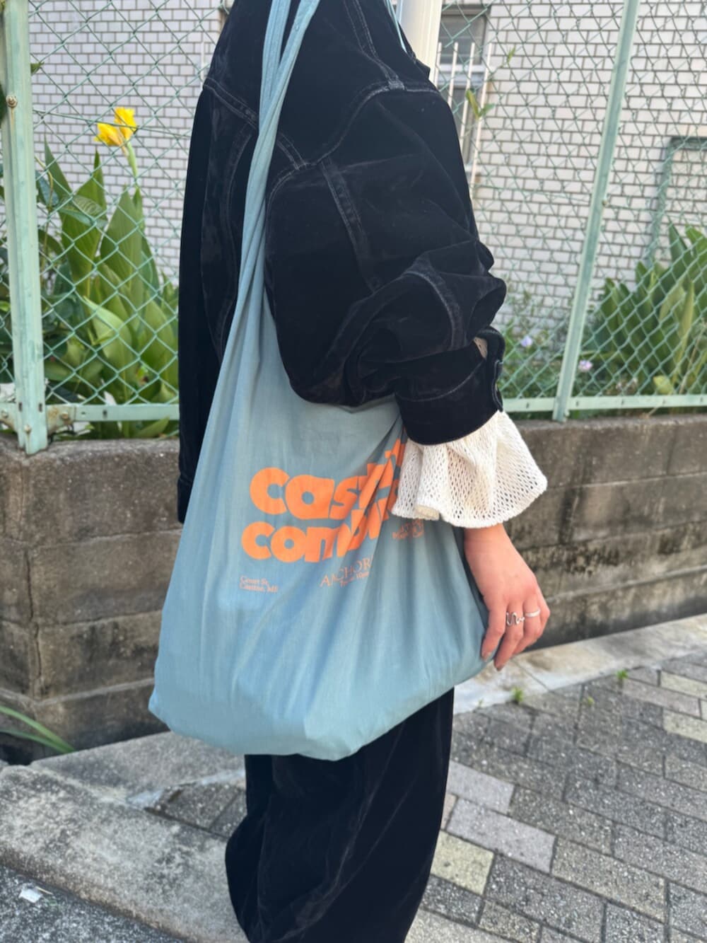 ブラック系のスリッポン、ブラック系のデニムパンツ、ブルー系のトートバッグを着用したレディースの夏コーディネートの7枚目の写真