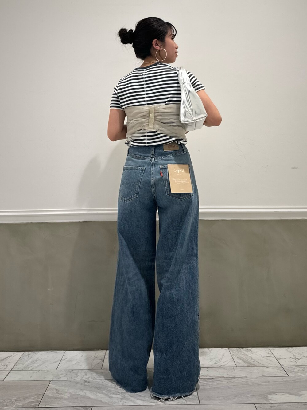 グレー系のTシャツ/カットソー、ベージュ系のキャミソール、ブルー系のデニムパンツを着用したレディースの春コーディネートの4枚目の写真