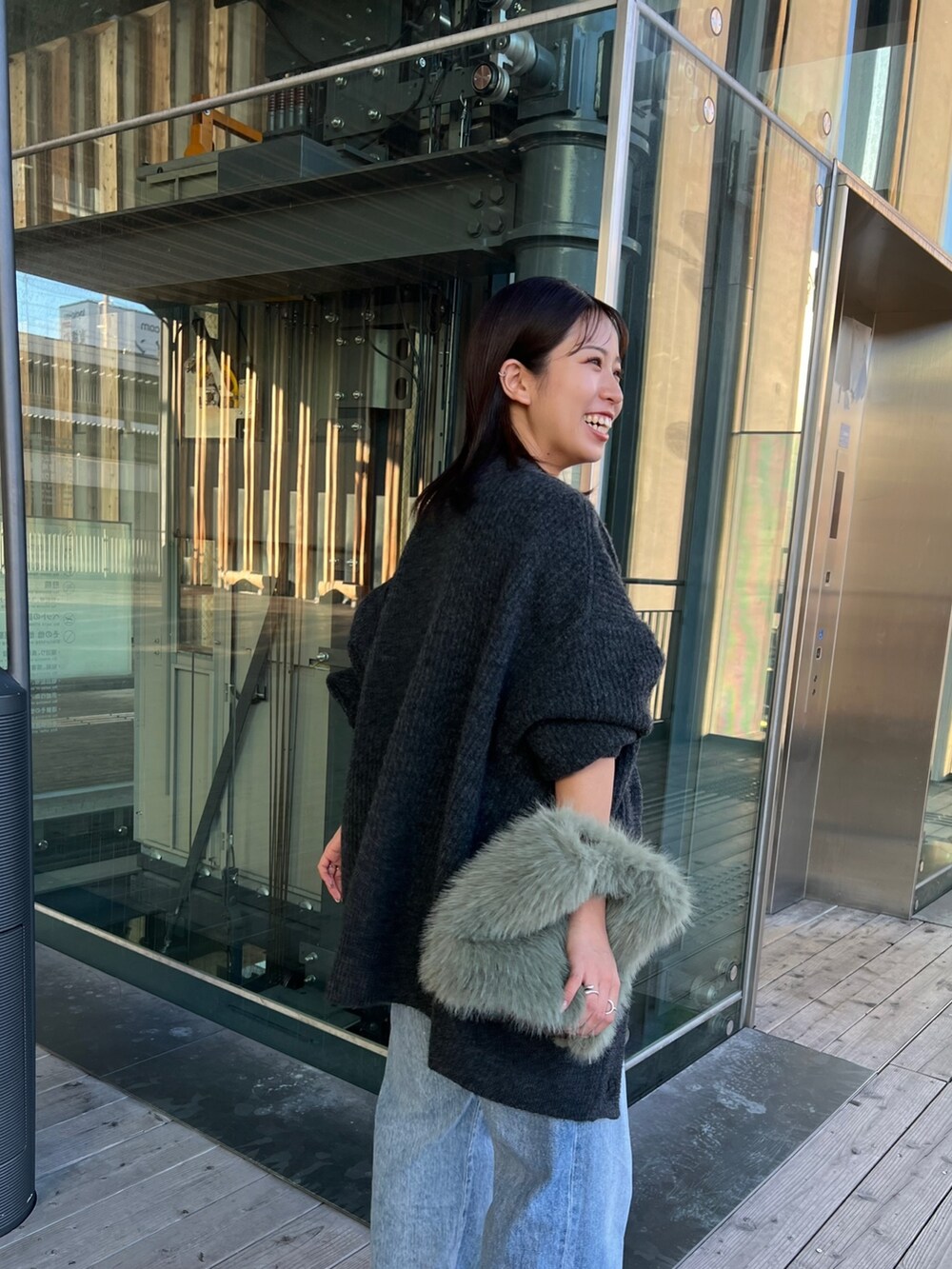 グレー系のカーディガン/ボレロ、ブラック系のキャミソール、ブルー系のデニムパンツを着用したレディースの秋コーディネートの3枚目の写真